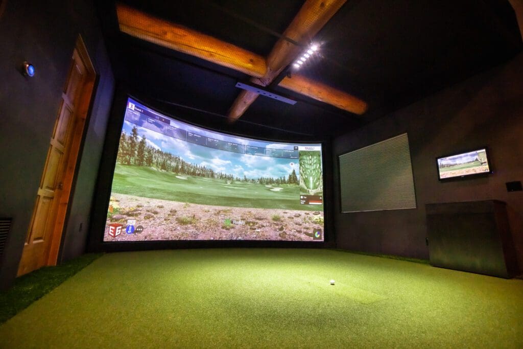 A golf simulator in a room with a tv.