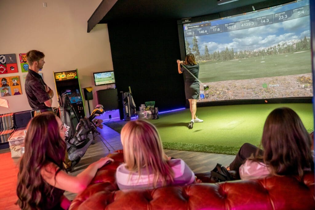 A group of people enjoying a game of golf in a Golf Simulator room.