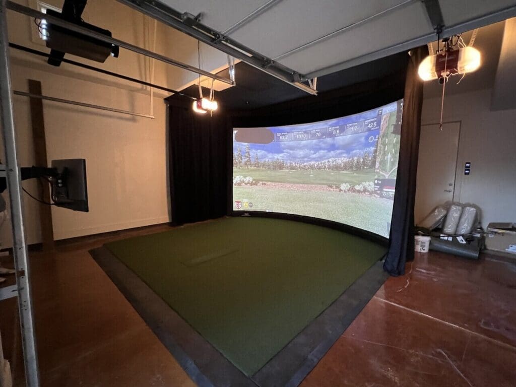 A garage with a large golf simulator screen.